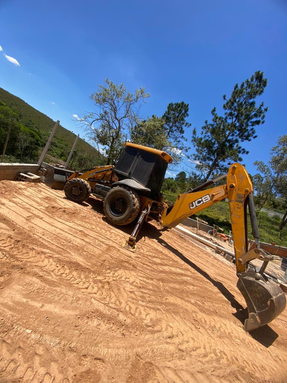 Retroescavadeira JCB em trabalho de terraplanagem