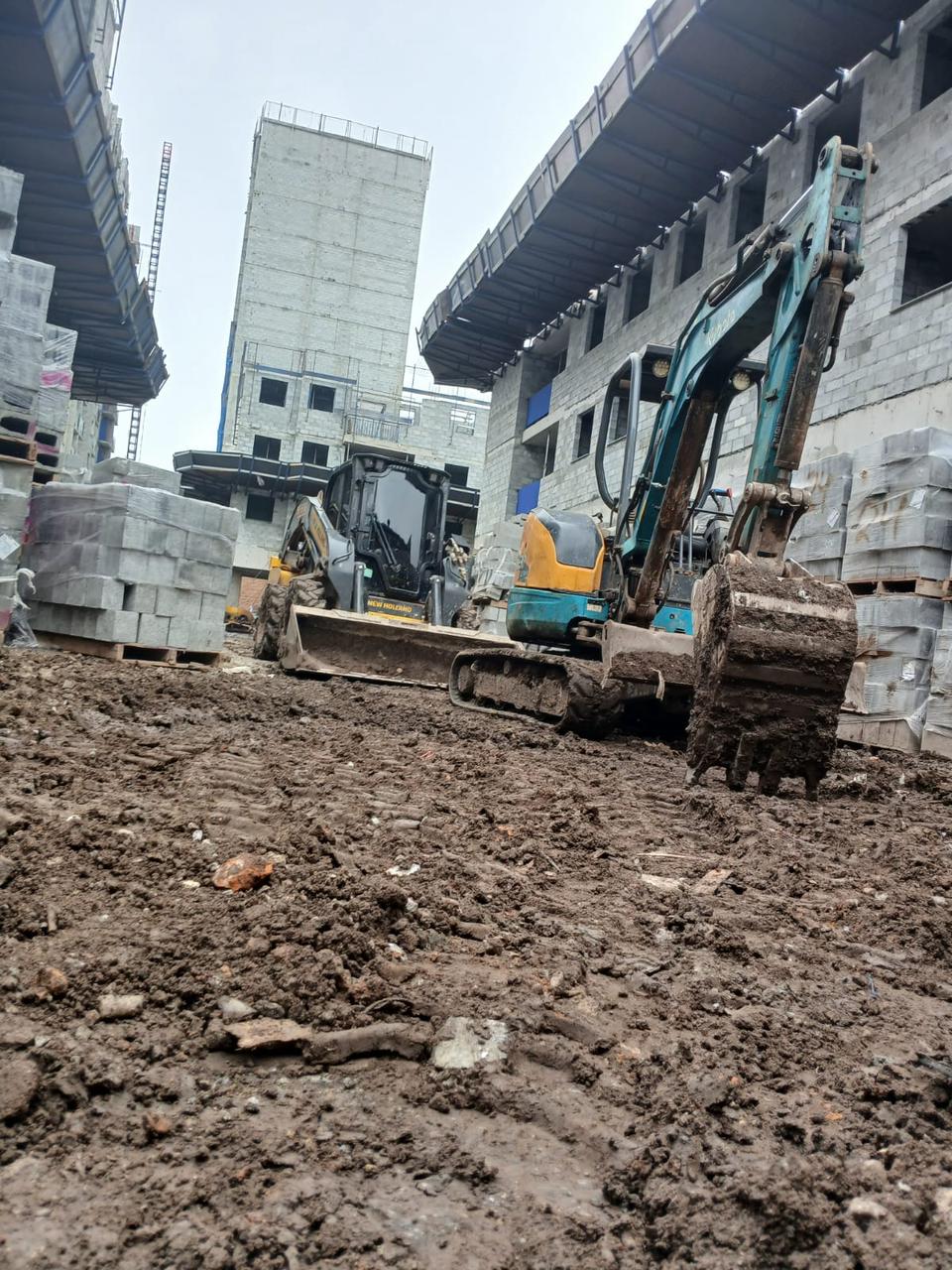 Mini carregadeira e escavadeira em operação no canteiro de obra
